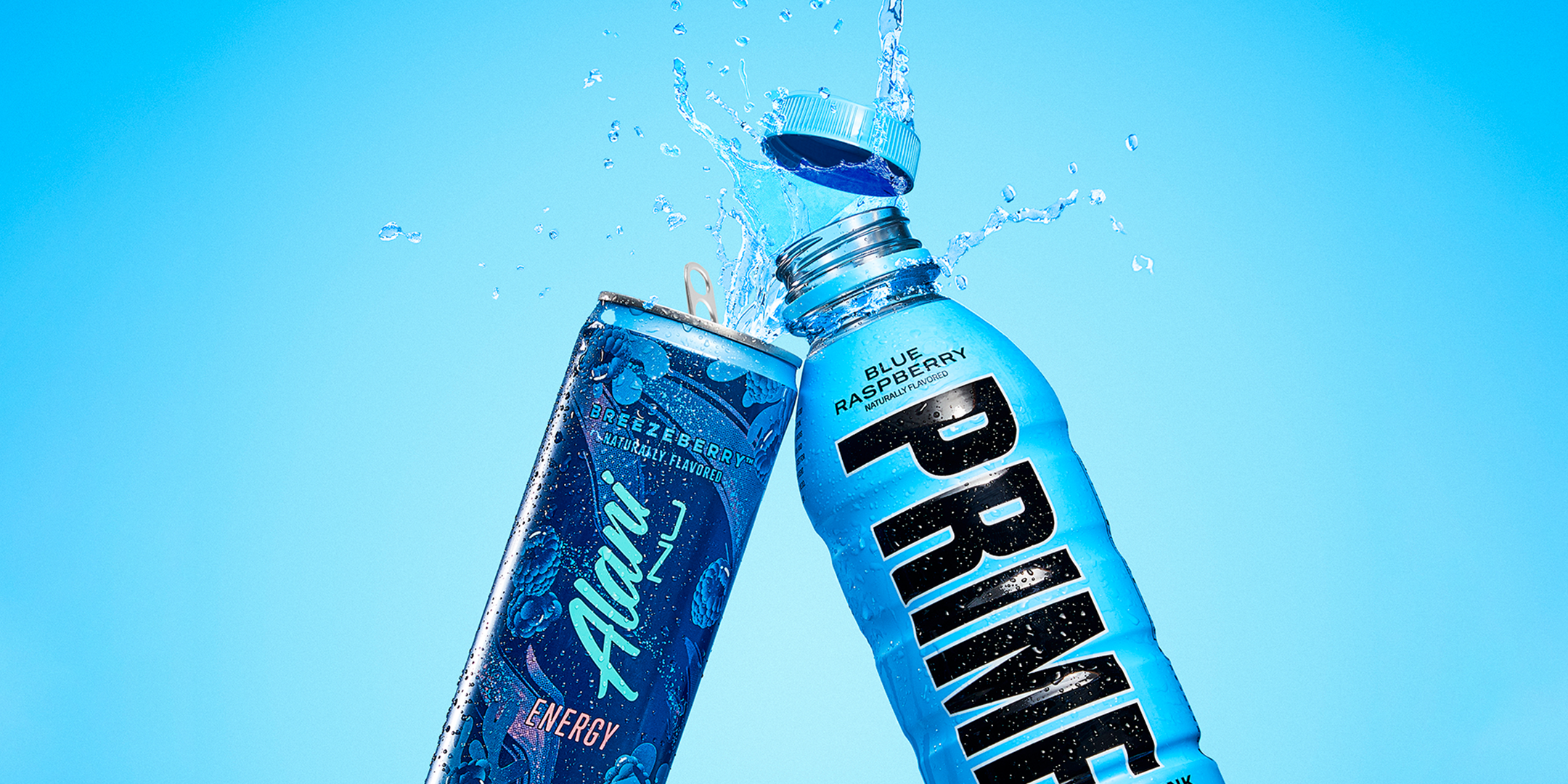 An energy drink in blue raspberry flavor splashing out of an open bottle next to a prime hydration bottle in blue raspberry flavor.